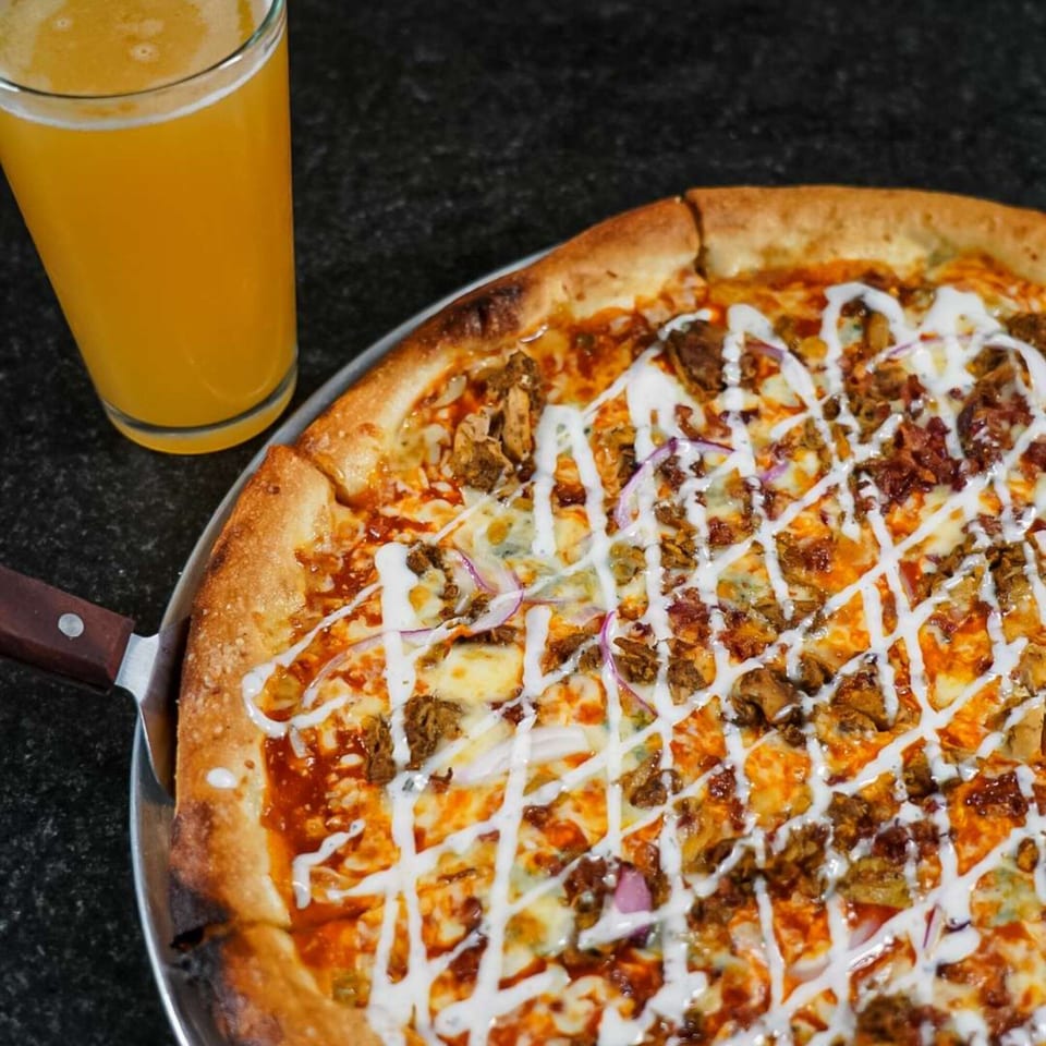 Ember + Ale's buffalo chicken pizza with ranch drizzle and a glass of beer.