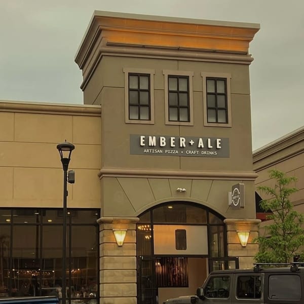 Exterior of Ember + Ale, a pizza restaurant, with its sign and arched entrance visible.