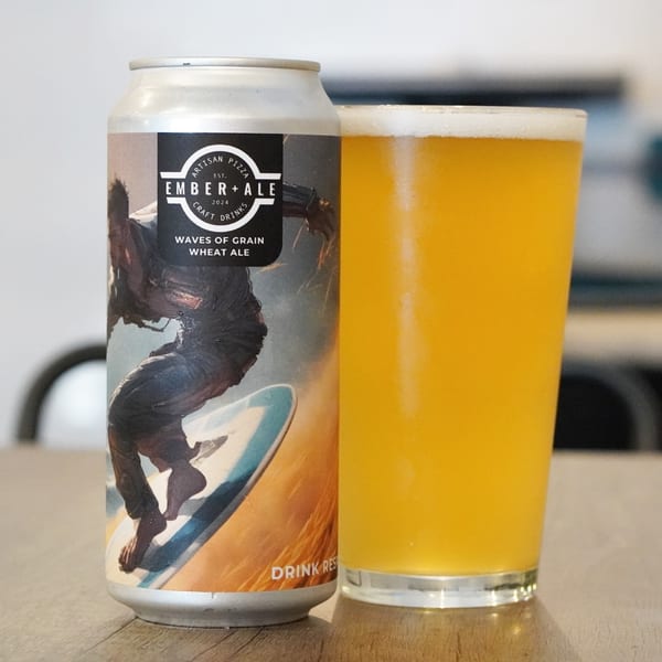 A can of Ember + Ale "Waves of Grain" Wheat Ale next to a glass of the golden beer.