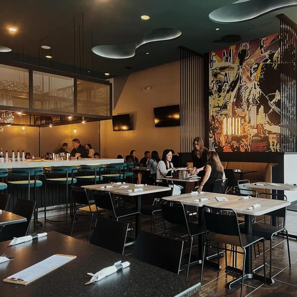 Ember + Ale's modern dining room with patrons, a bar, and a large abstract mural.